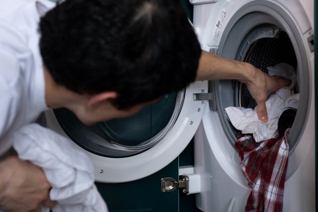 a guy getting clothes from washing machine